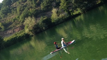 Una persona remando un canoa en un río tranquilo rodeado de abundante vegetación.