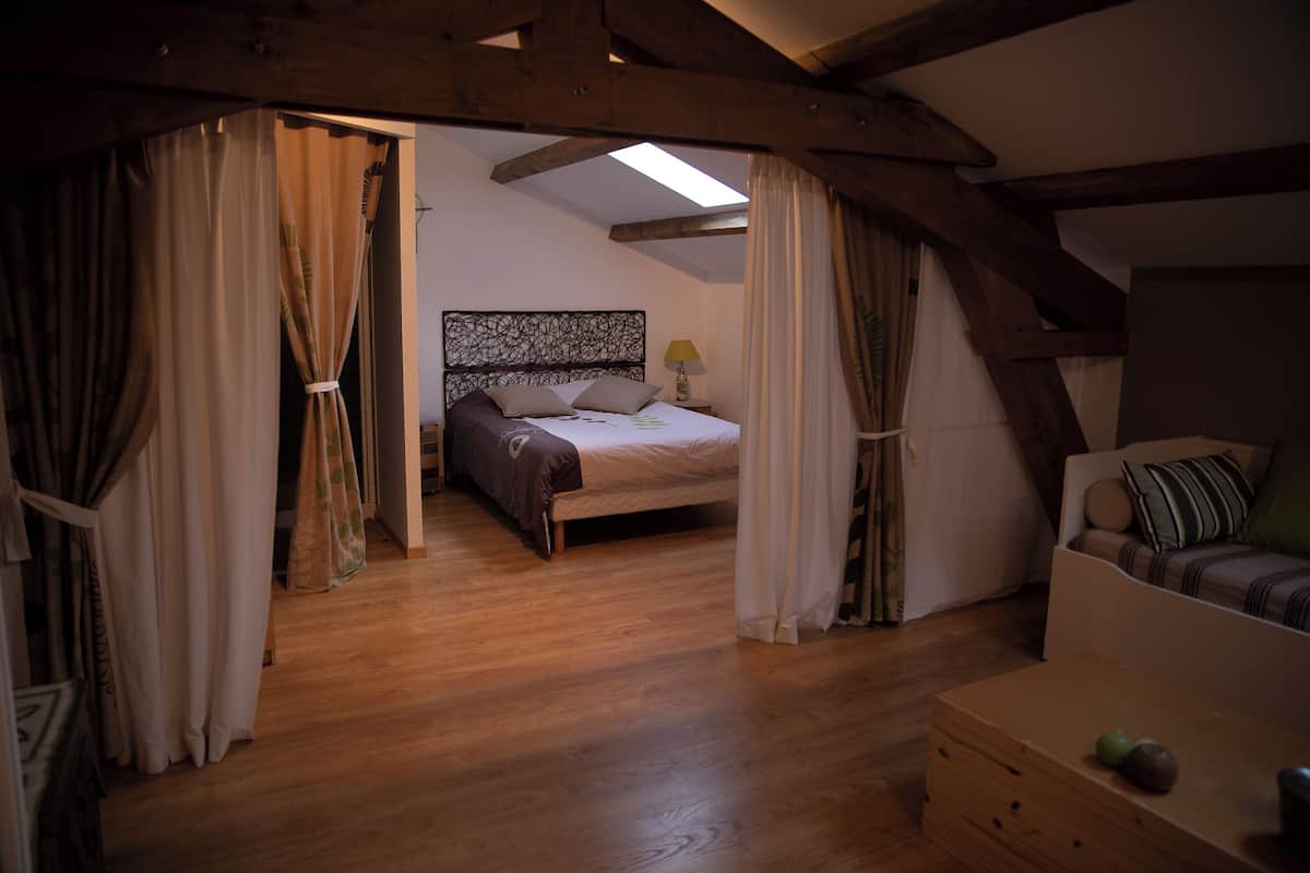 A bedroom with a wooden ceiling, a bed with a headboard, and a nightstand with a lamp.