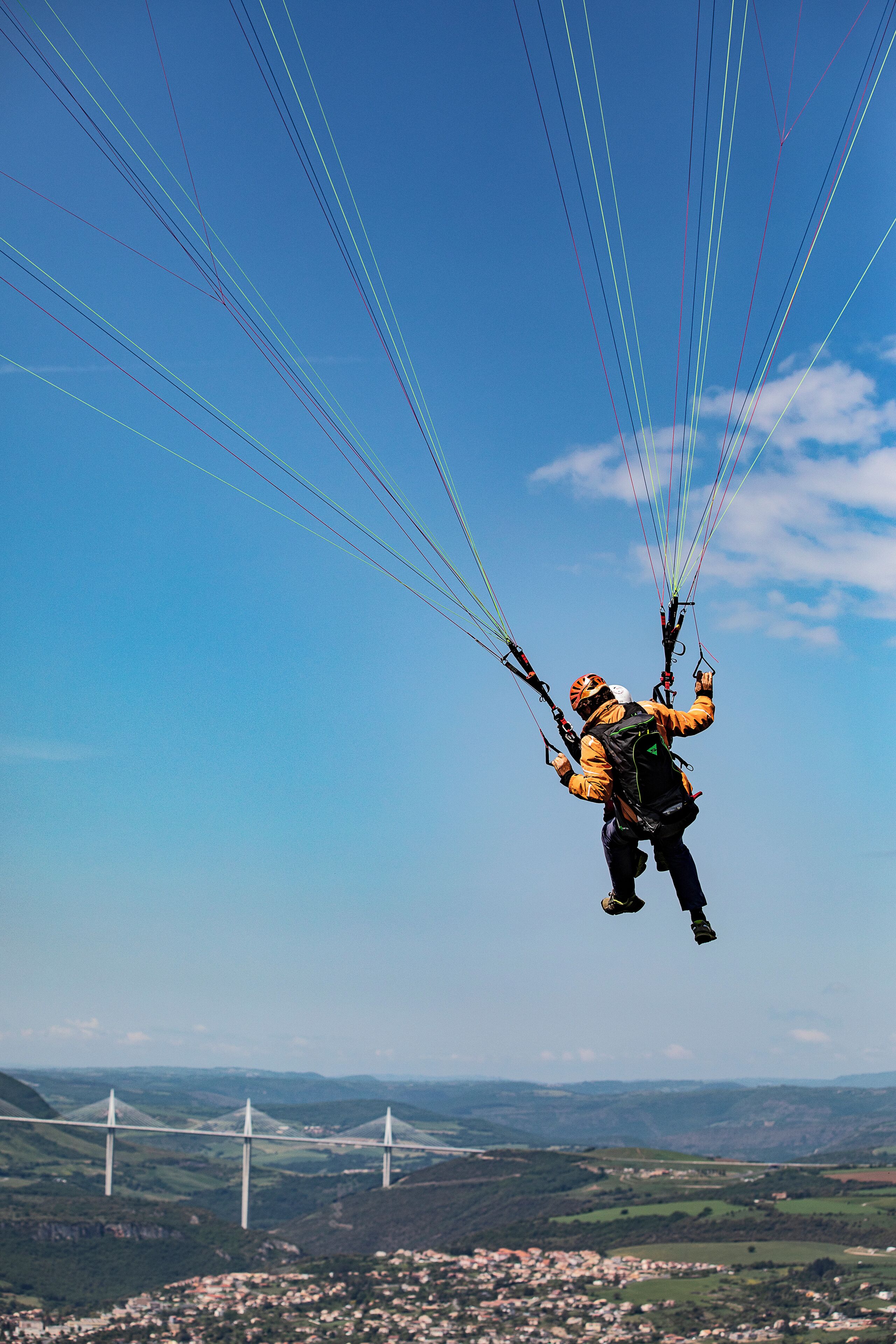 Una persona practicando parapente, con varias líneas que se extienden desde el planeador.