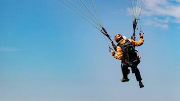 Una persona practicando parapente, con varias líneas que se extienden desde el planeador.