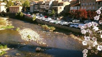 Un río con un puente, edificios al fondo y coches estacionados.