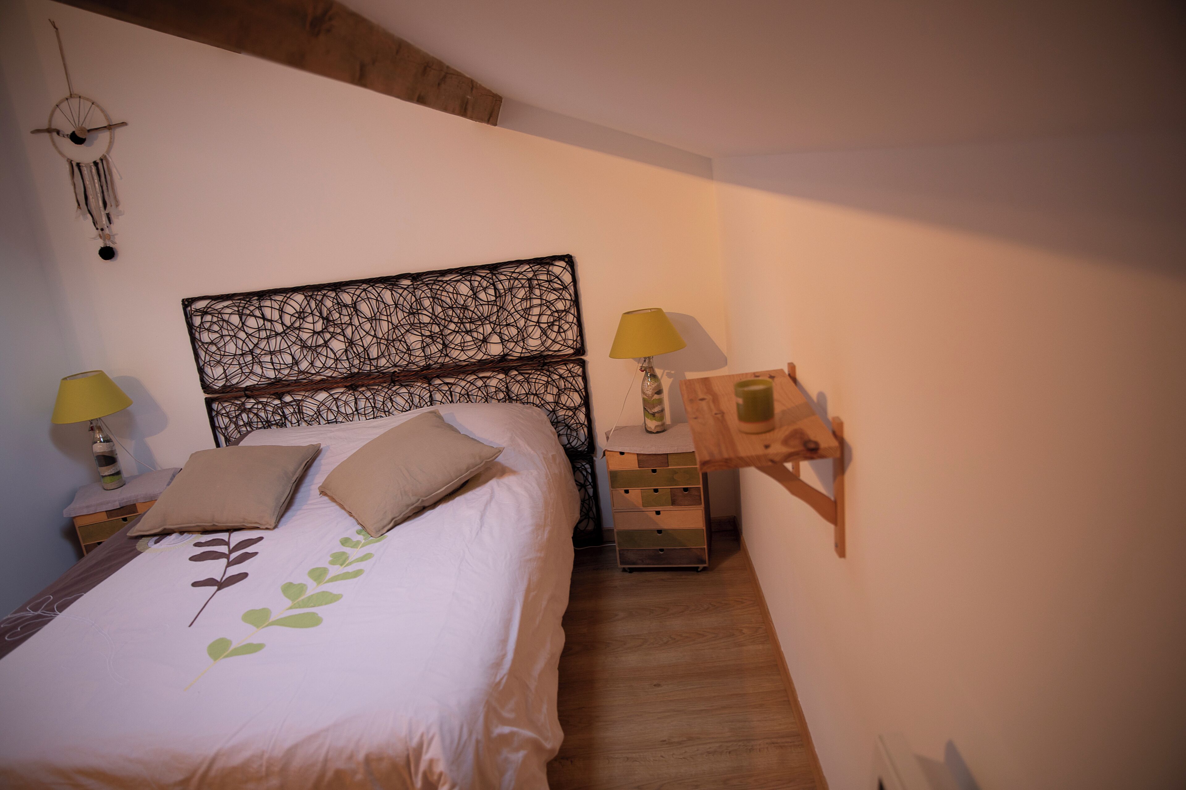 Un dormitorio con una cama, dos lámparas de noche, una mesita de noche y un estante en la pared.