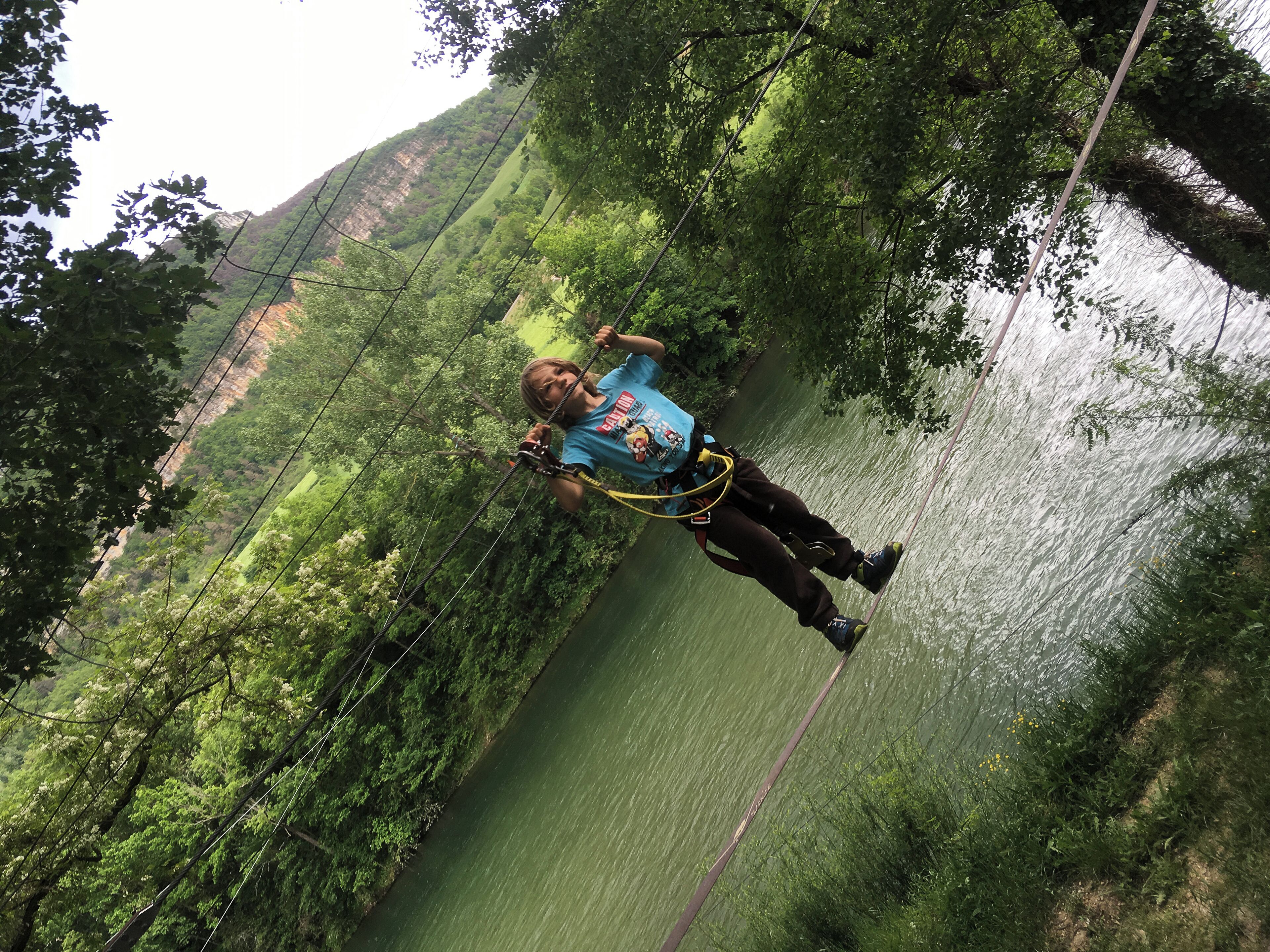 Eine Person macht Bungeejumping von einer Brücke über einem Fluss, umgeben von üppiger Vegetation und Hügeln.