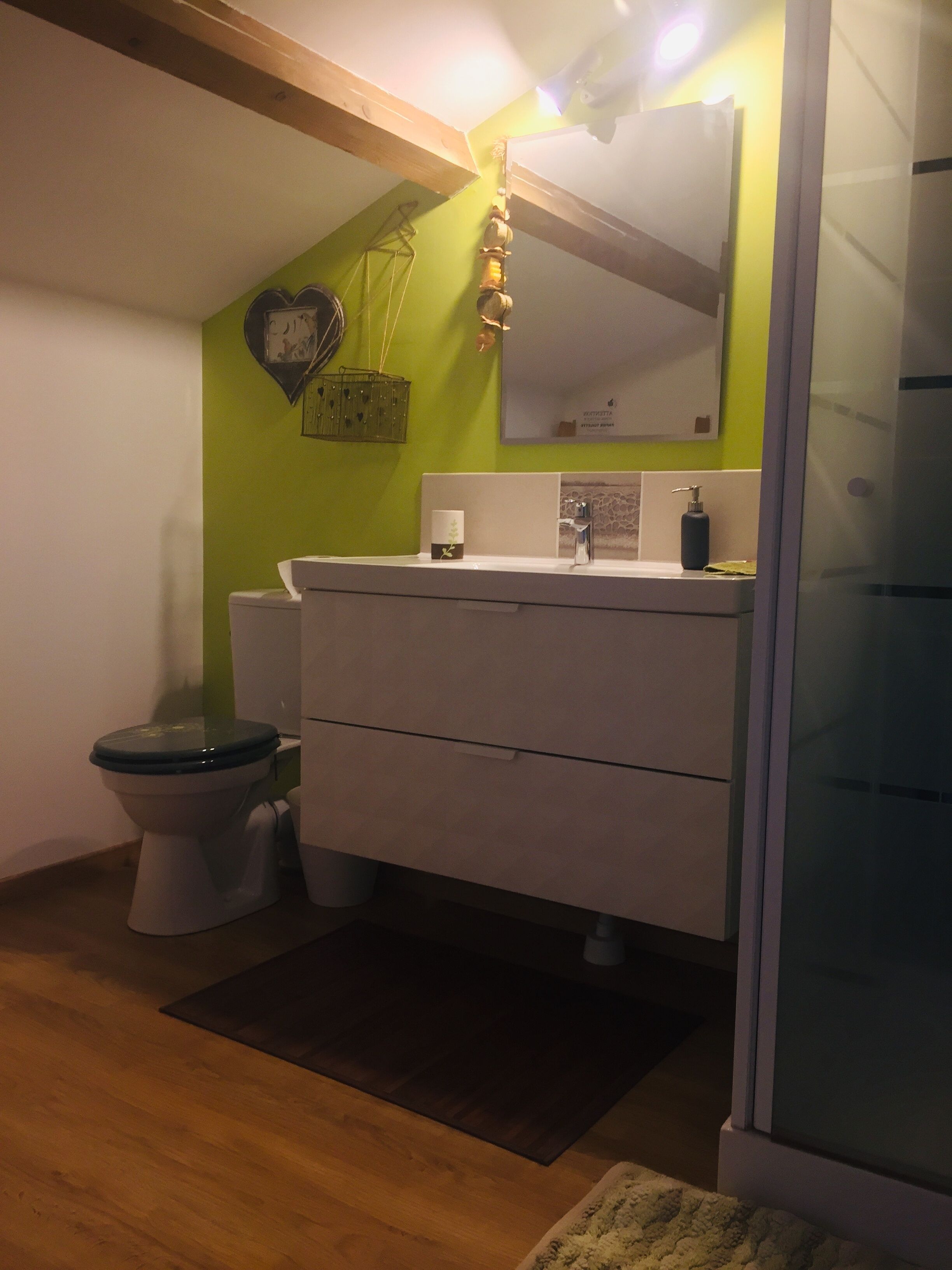 A bathroom with a toilet, sink, and mirror.