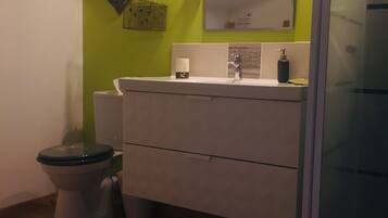 A bathroom with a toilet, sink, and mirror.