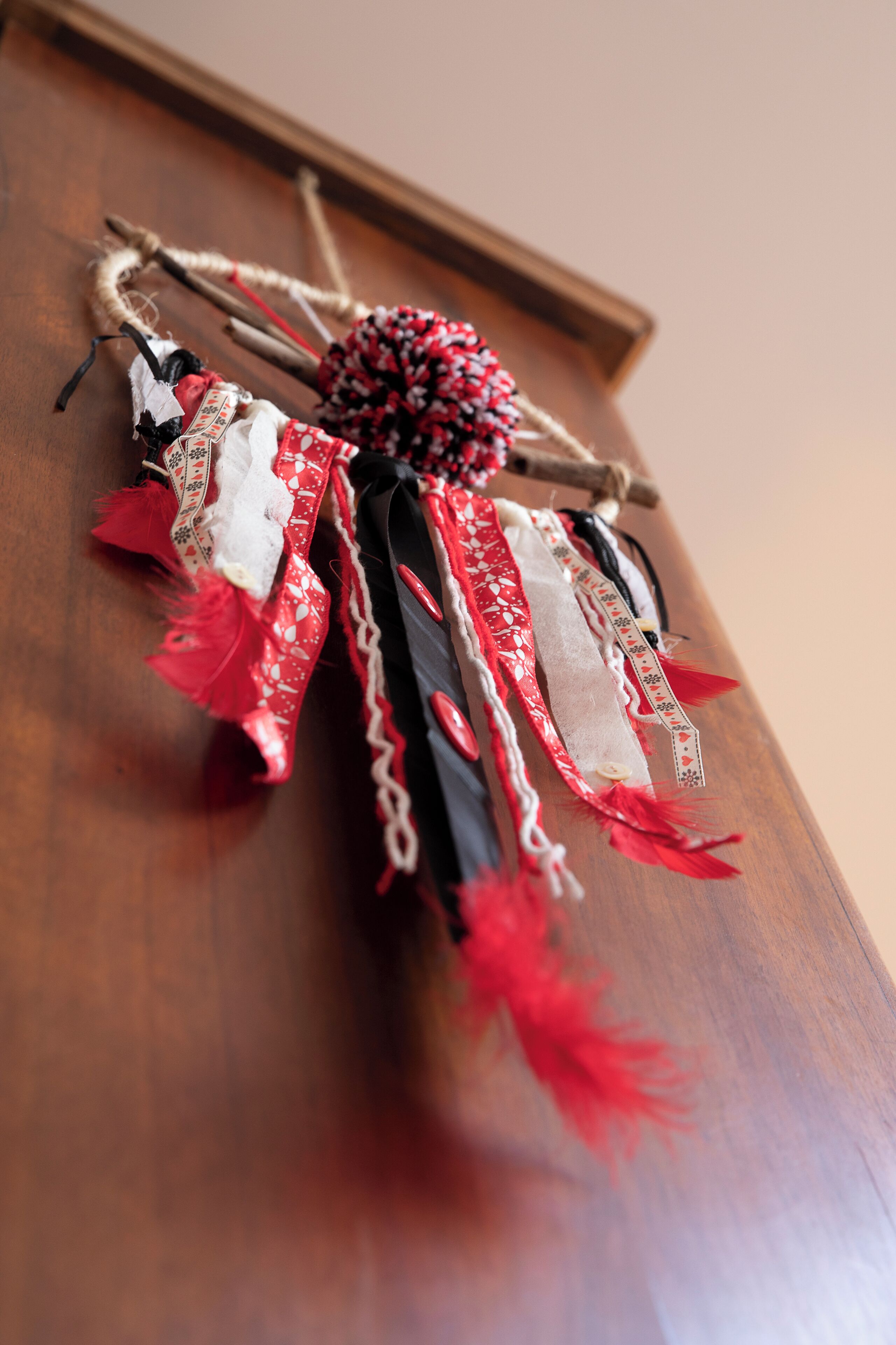 A decorative item with red, white, and black ribbons and feathers.