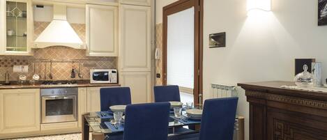 Una cocina moderna con armarios blancos, un microondas y un comedor con sillas azules y una mesa.