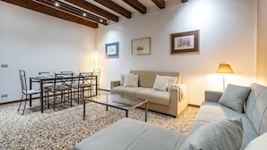 A furnished living room with a sofa, a glass coffee table, a dining table with chairs, and a lamp. - San Moisé (Venice)