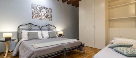 A bedroom with a bed, bedside tables, a wardrobe, and a ceiling with exposed beams.