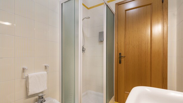 Une salle de bain avec une douche, un lavabo et une porte en bois.