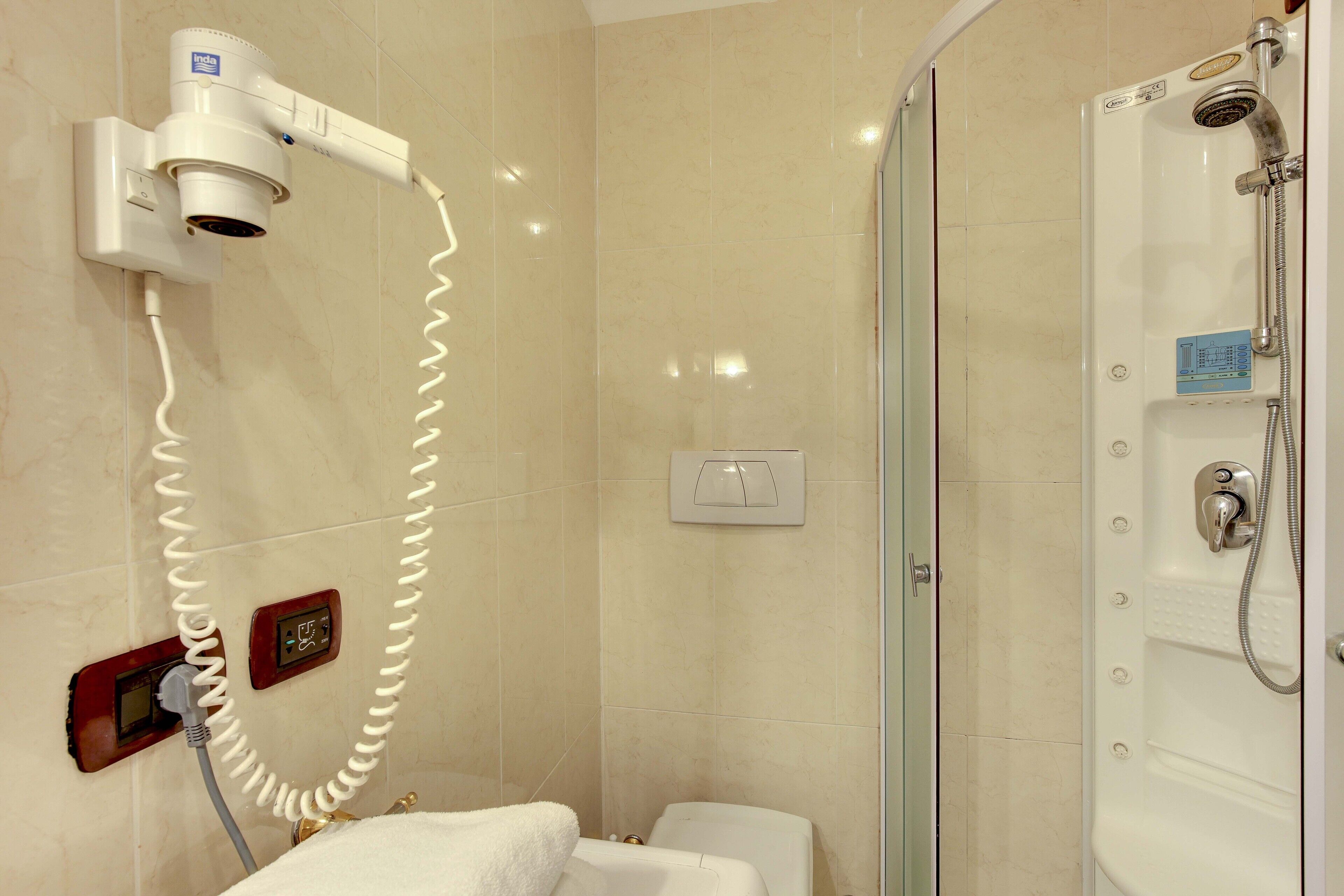 A bathroom with a hairdryer, a shower, and a towel rack.