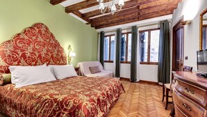 A hotel room with a large bed, wooden ceiling beams, a dresser, and a TV. - San Marco Superior Apartments by Wonderful Italy (Venice)