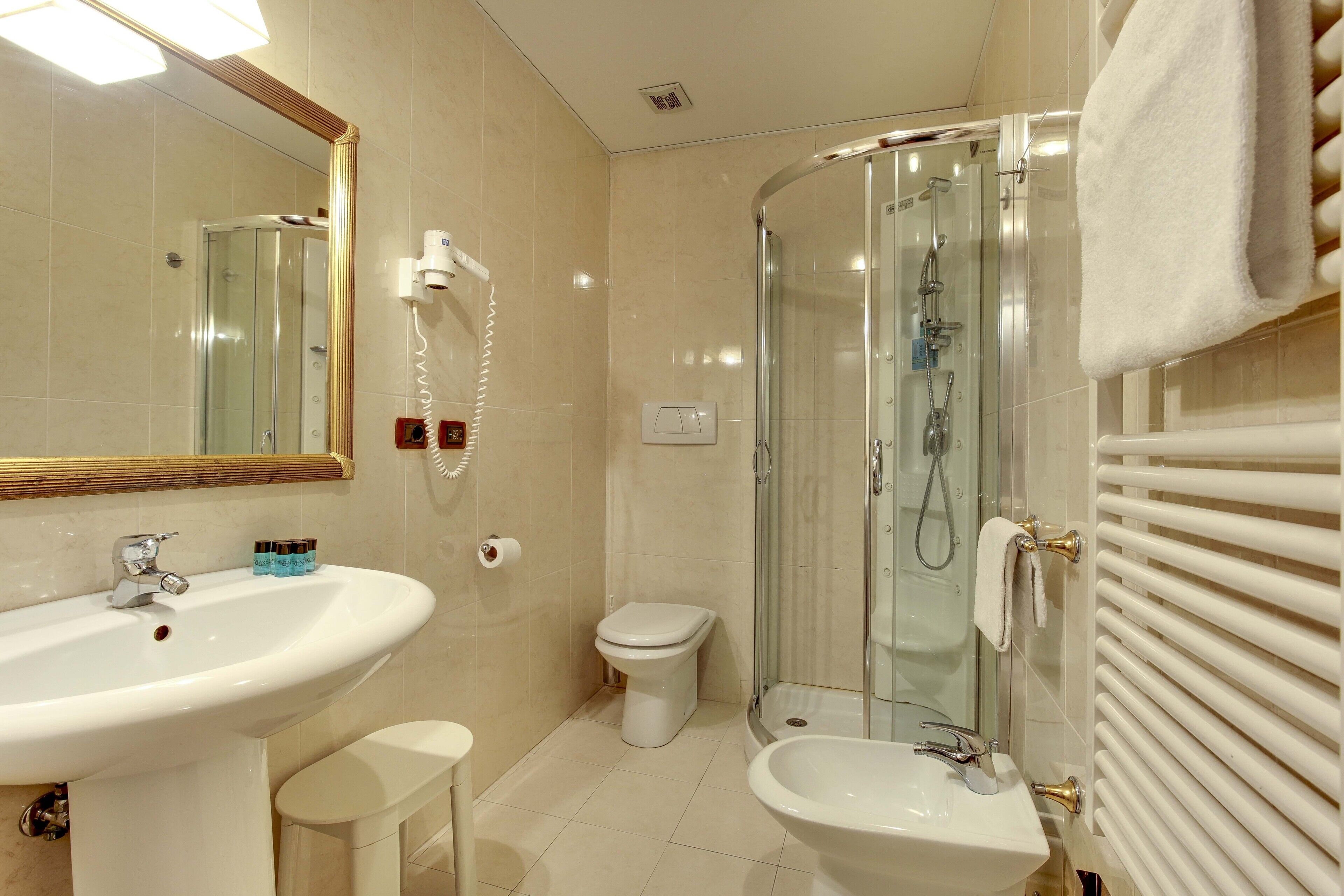 A bathroom with a sink, bidet, toilet, and glass-enclosed shower.