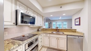 Una cocina moderna con armarios blancos, microondas integrado, estufa y lavavajillas.