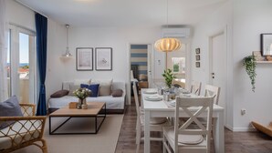 A modern living room with a sofa, coffee table, and dining area. There is a view of a bedroom through an open door. - Villa Valentina (Bol)