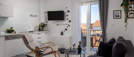 A modern living space with a kitchen, a dining area, and a balcony with a view.