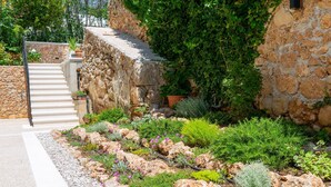A stone staircase leading to a garden with various plants and a stone wall. - Villa Valentina (Bol)