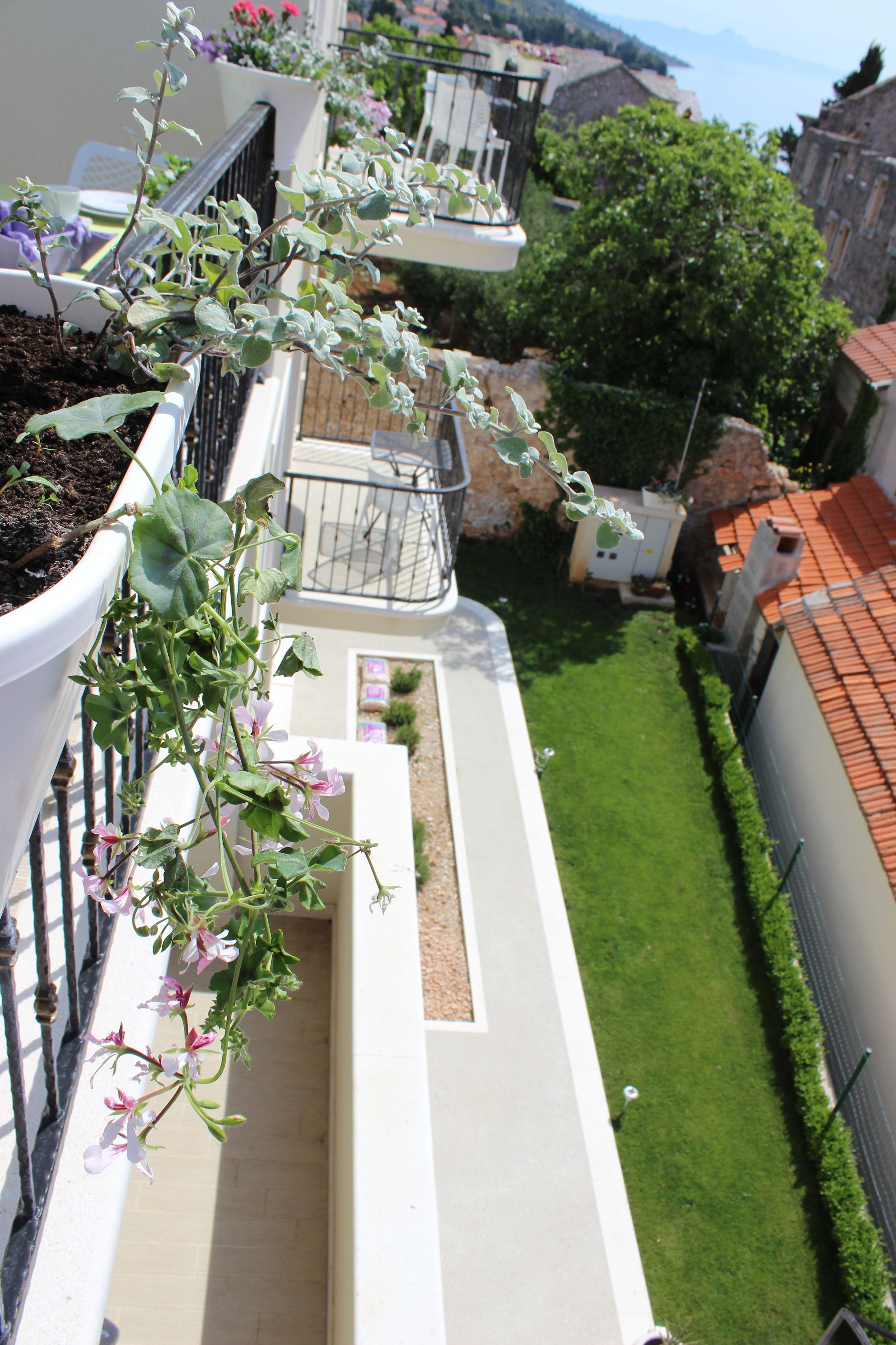 Een balkon met een bloempot en uitzicht op een verzorgd gazon en gebouwen.