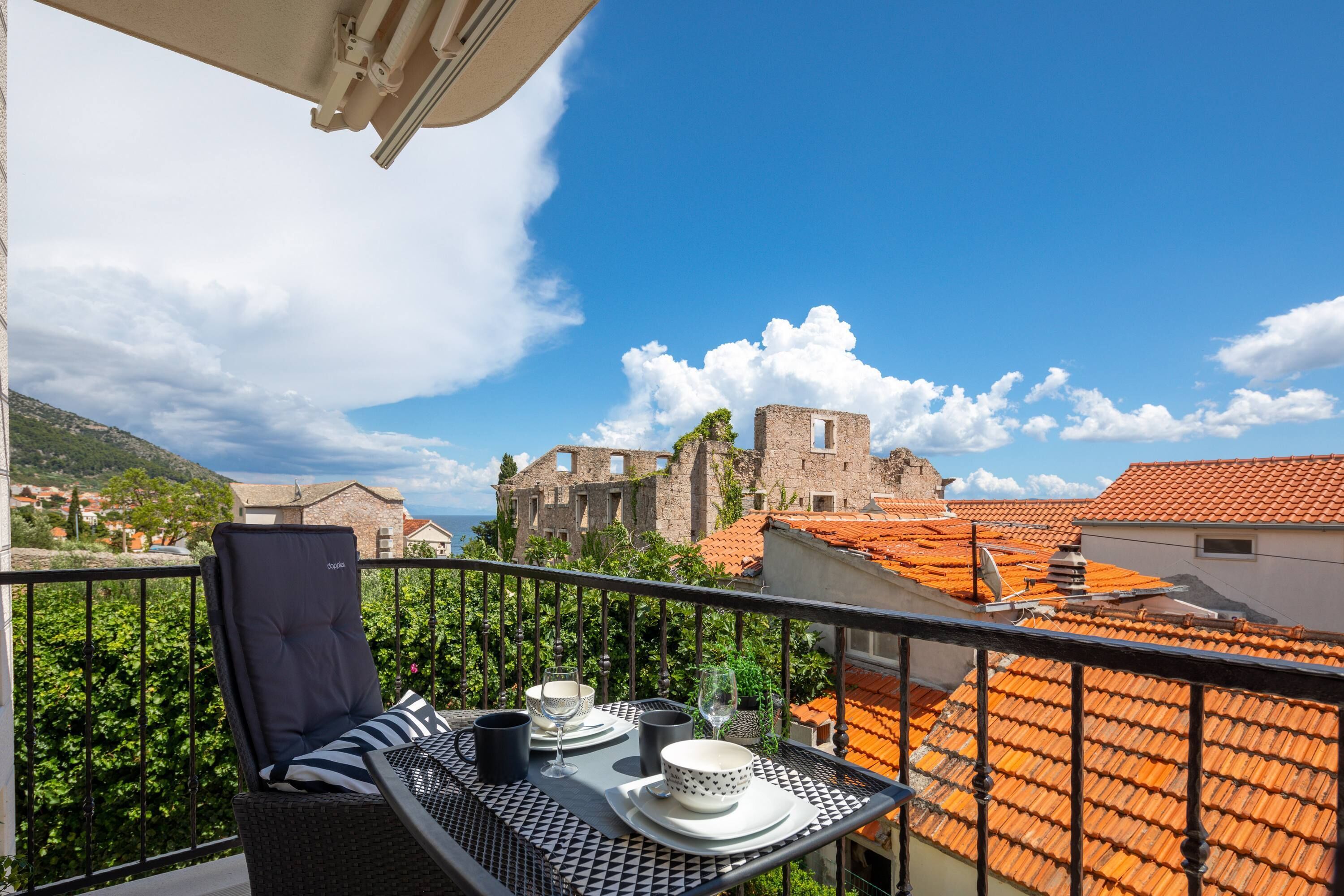 A balcony with a table set for two, overlooking a historic building and terraced houses.