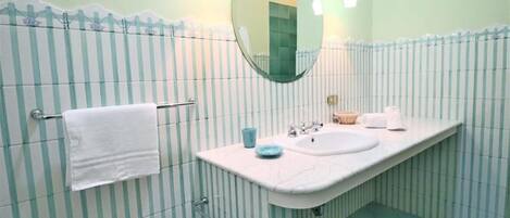 Ein Badezimmer mit gestreifter Wandgestaltung, einem weißen Waschbecken, einem Spiegel und einem Handtuchhalter.