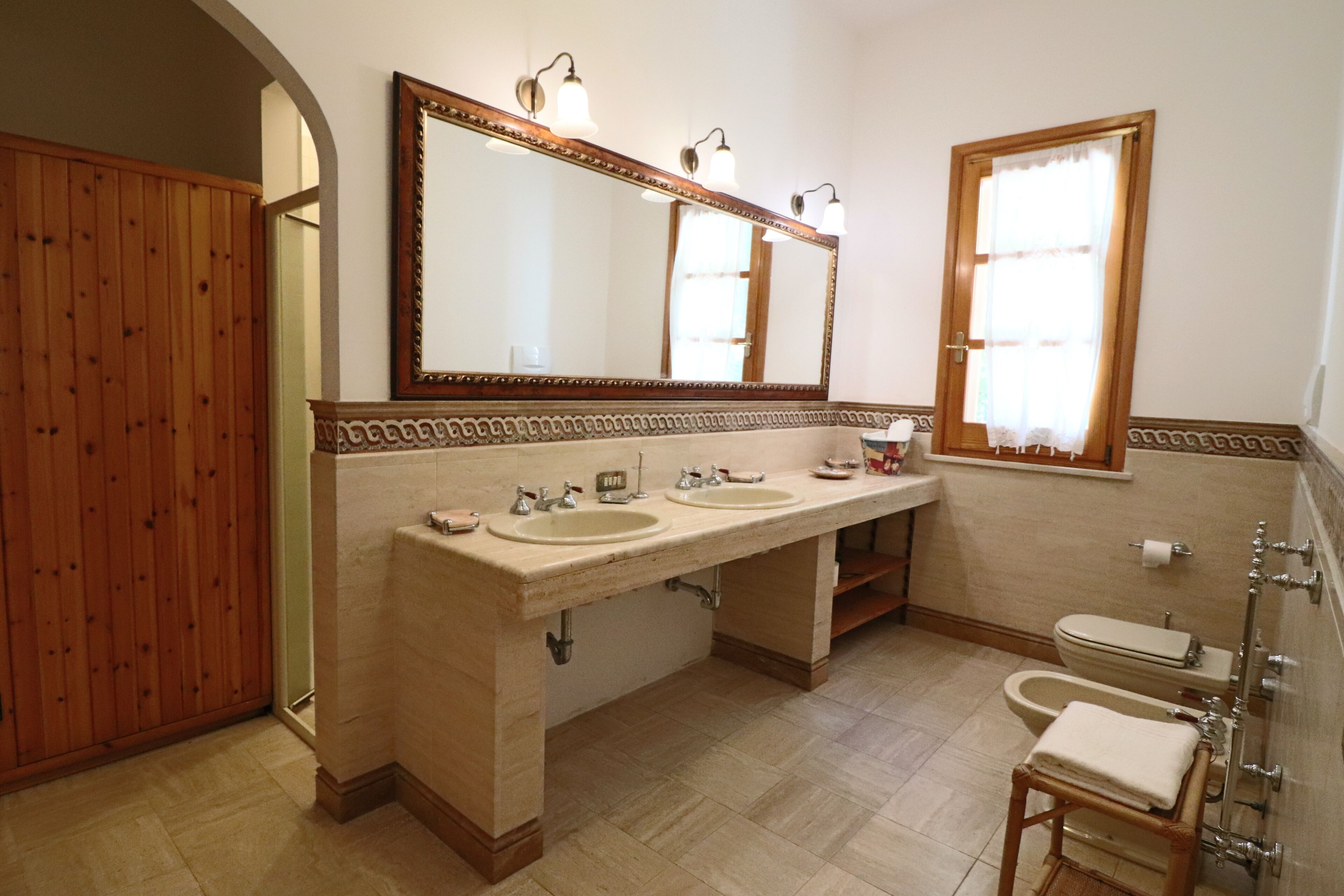 Un baño con dos lavamanos, un espejo grande, un inodoro y una bañera.
