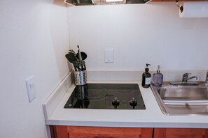 A kitchen with a black stove, a sink, and wooden cabinets.