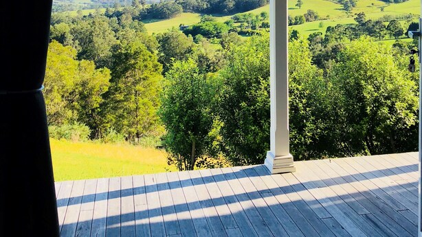 Eine Holzterrasse mit Blick auf eine grüne Landschaft unter einem Metalldach.