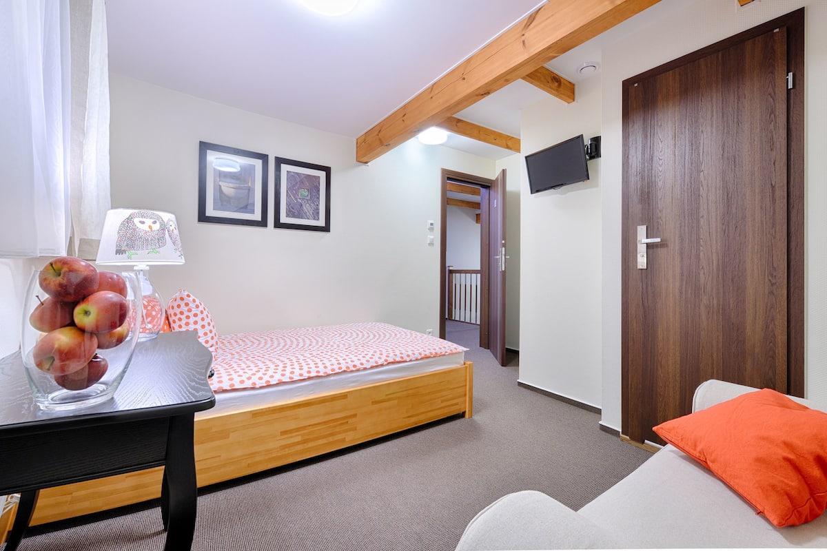 Une chambre avec un lit, un bureau doté d’une lampe et un téléviseur fixé au mur.