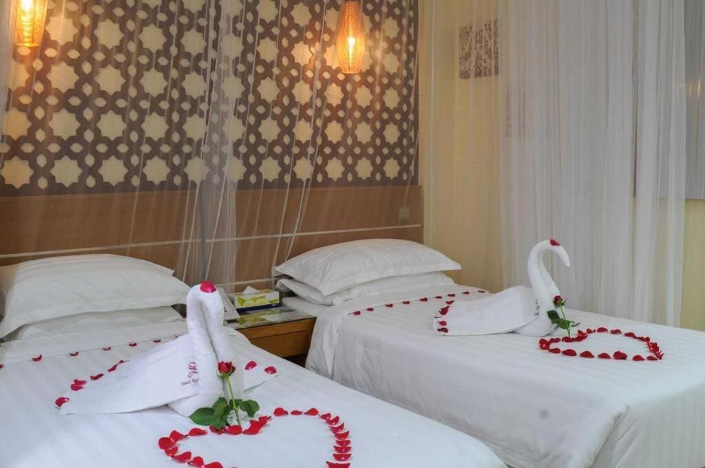 Ein Hotelzimmer mit zwei Betten, verziert mit Schwänen und Rosenblättern.