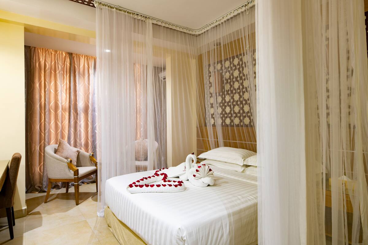 A hotel room with a bed, a chair, and a decorative wall pattern.