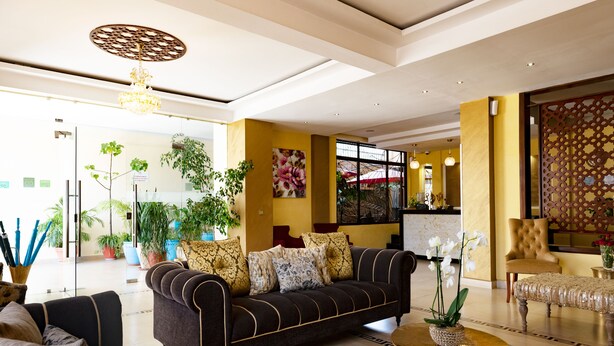 A modern lobby with a sofa, a coffee table, and potted plants. - Saab Royale Hotel (Nairobi)