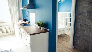 A modern kitchen with a wooden countertop, white cabinets, and a blue accent wall. - Hevals Grand Tempelhof (Berlin)