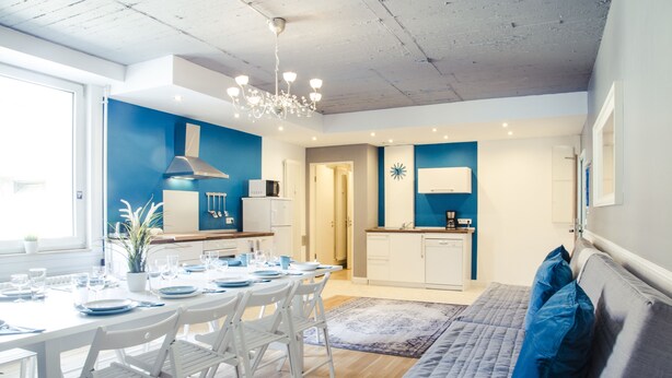 A modern kitchen with white cabinets, a built-in microwave, and a stainless steel range hood. - Hevals Grand Tempelhof (Berlin)