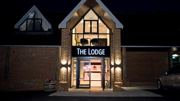 A brick building with a triangular roof and a sign reading "The Lodge." - The Lodge at Kingswood (Tadworth)