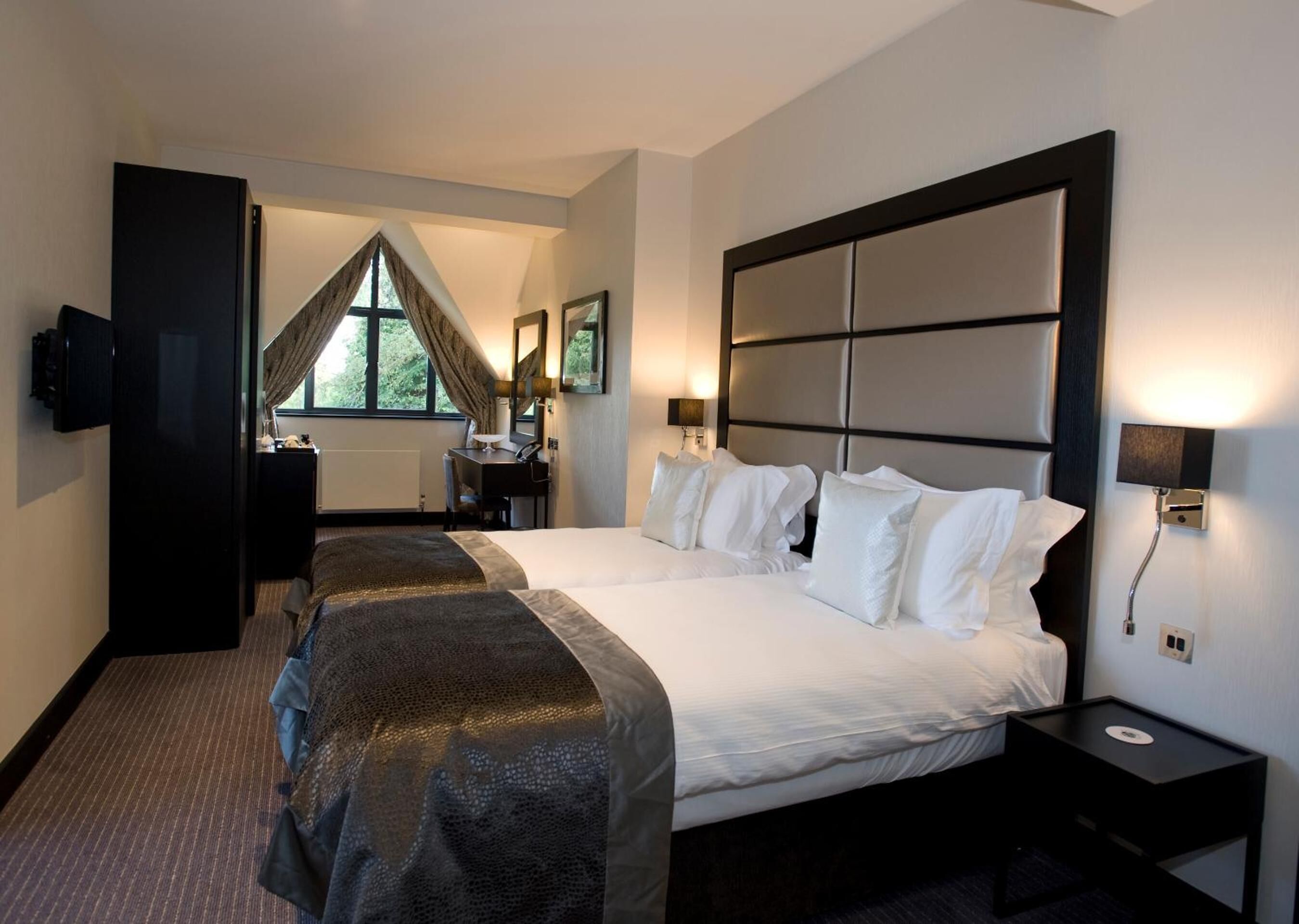A hotel room with a large bed, a desk, and a TV.