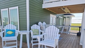 A covered outdoor deck with white Adirondack chairs and a patterned rug. - Kids Cottage Amazing views from all directions (Jamaica Beach)