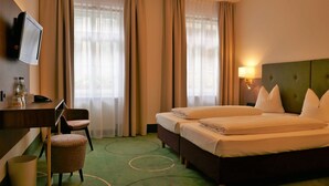 Een hotelkamer met een bed, een bureau met stoel, een aan de muur bevestigde televisie en een lamp.