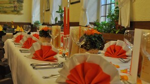 Een eettafel gedekt met oranje en witte servetten, wijnglazen en bestek.