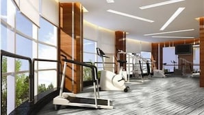 Un gimnasio moderno con cintas de correr, máquinas de pesas y una gran pantalla de televisión.