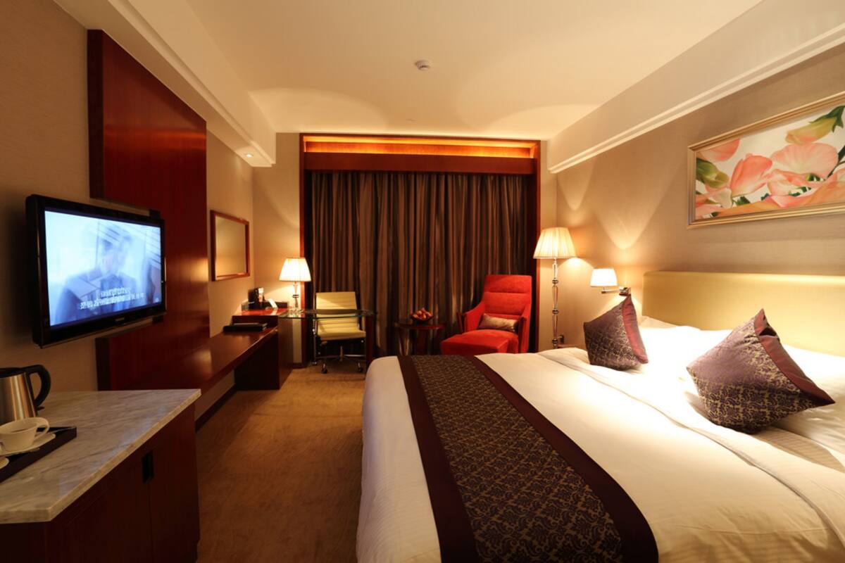 Een hotelkamer met een bed, een televisie, een bureau met een koffiezetapparaat, een stoel en een lamp.