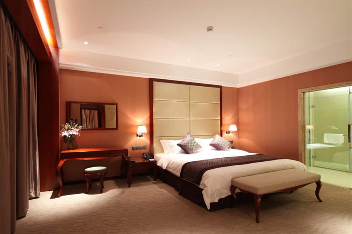 Een hotelkamer met een groot bed, bedlampjes, een bureau en een stoel.