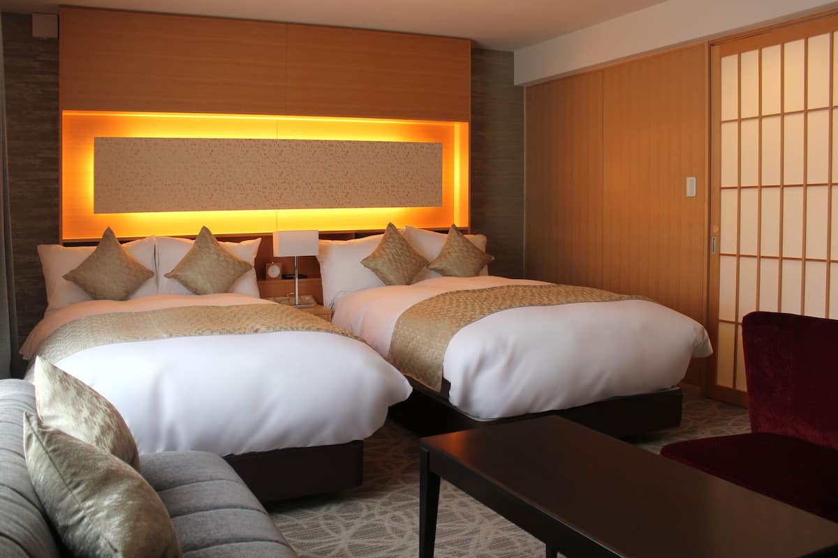 Ein Hotelzimmer mit zwei Betten, einem Sofa, einem Tisch und einer traditionellen Schiebetür.