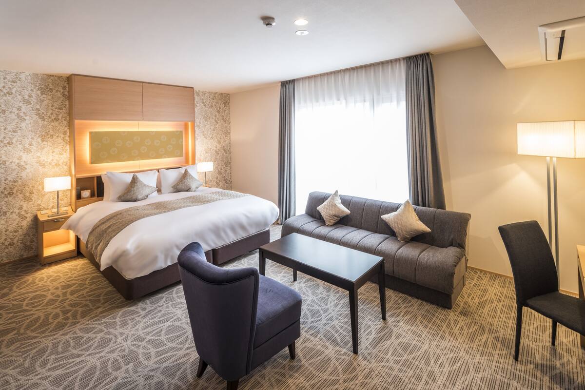 Ein Hotelzimmer mit einem großen Bett, einer Couch, einem Couchtisch und einem Sessel.