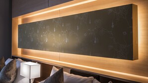 A modern hotel room with a large wall-mounted artwork, a bedside lamp, and a neatly made bed with pillows. - Kyoto Shinmachi Rokkaku Hotel grandereverie (Kyoto)