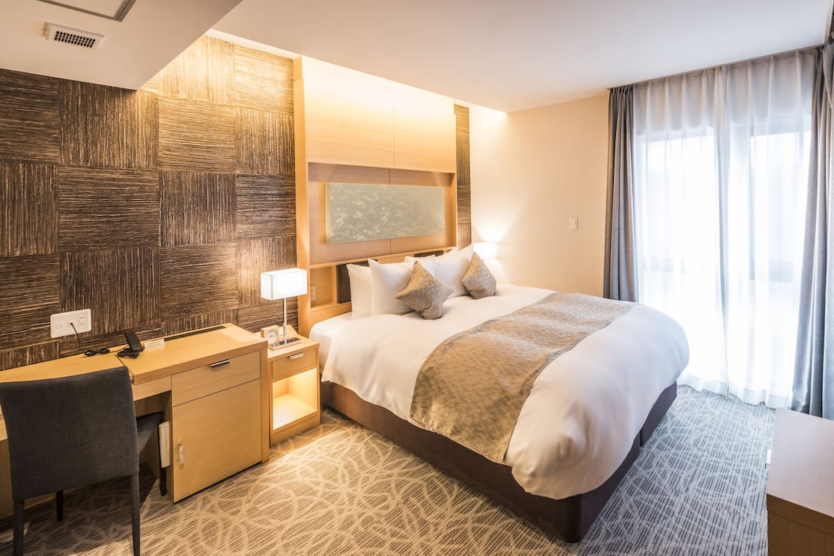 Ein Hotelzimmer mit einem großen Bett, einem Schreibtisch und einem Stuhl.