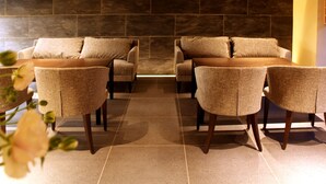 A seating area with sofas and chairs, a tiled floor, and a stone wall. - Kyoto Shinmachi Rokkaku Hotel grandereverie (Kyoto)