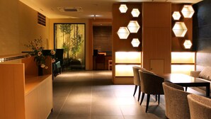 A hotel lobby with a reception desk, seating area, and hexagonal wall lights. - Kyoto Shinmachi Rokkaku Hotel grandereverie (Kyoto)