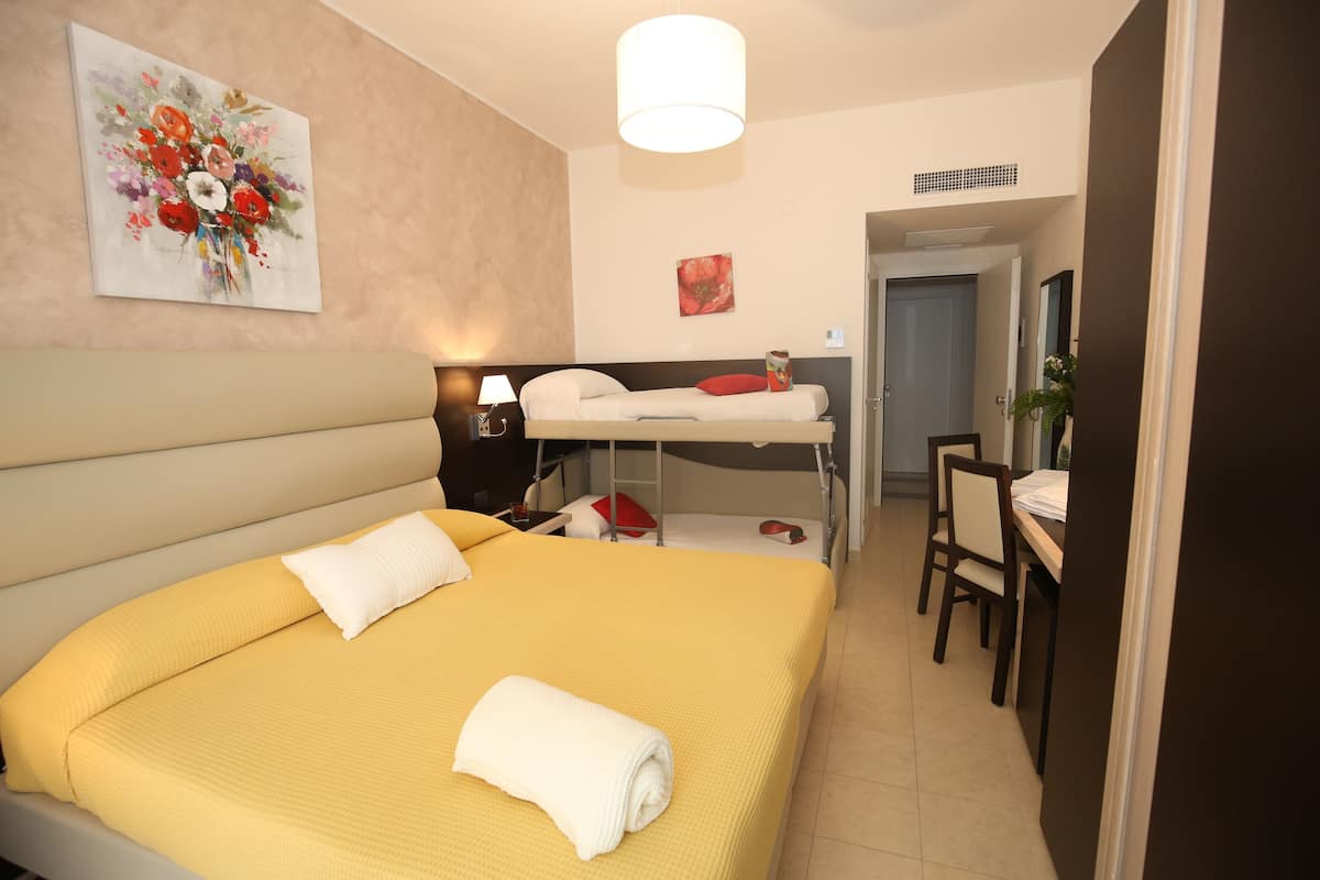Una camera d'albergo con un letto singolo, una scrivania e una sedia.