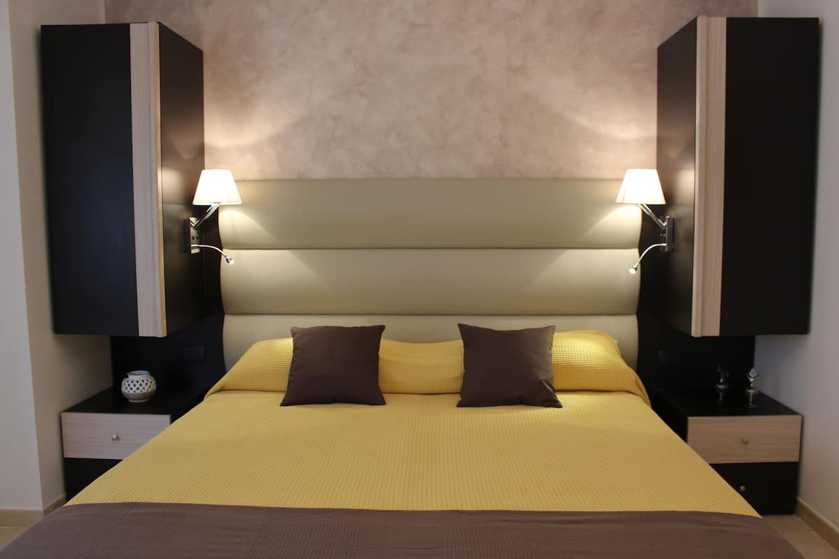 Una camera d'albergo con un letto grande, due comodini e una testiera.