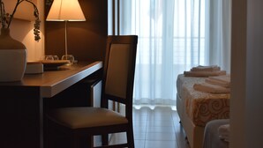 A hotel room with a desk, chair, lamp, bedside table, and a bed with a patterned bedspread. - Miramare Scilla GYH Luxury (Scilla)
